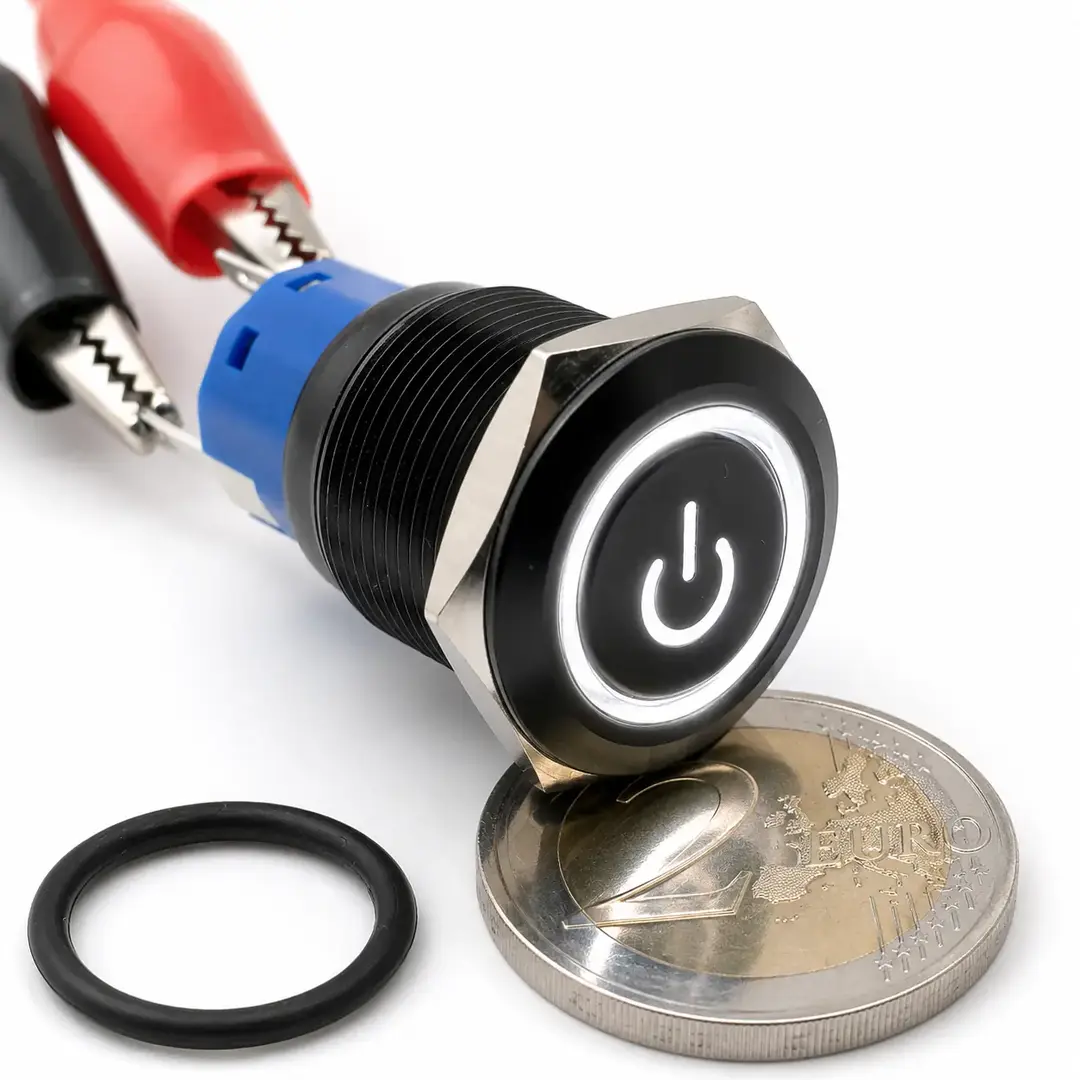Pulsante monostabile da pannello Ø19 mm con corpo nero, simbolo Power e anello LED bianco 12 V, mostrato con guarnizione e moneta da 2 euro.