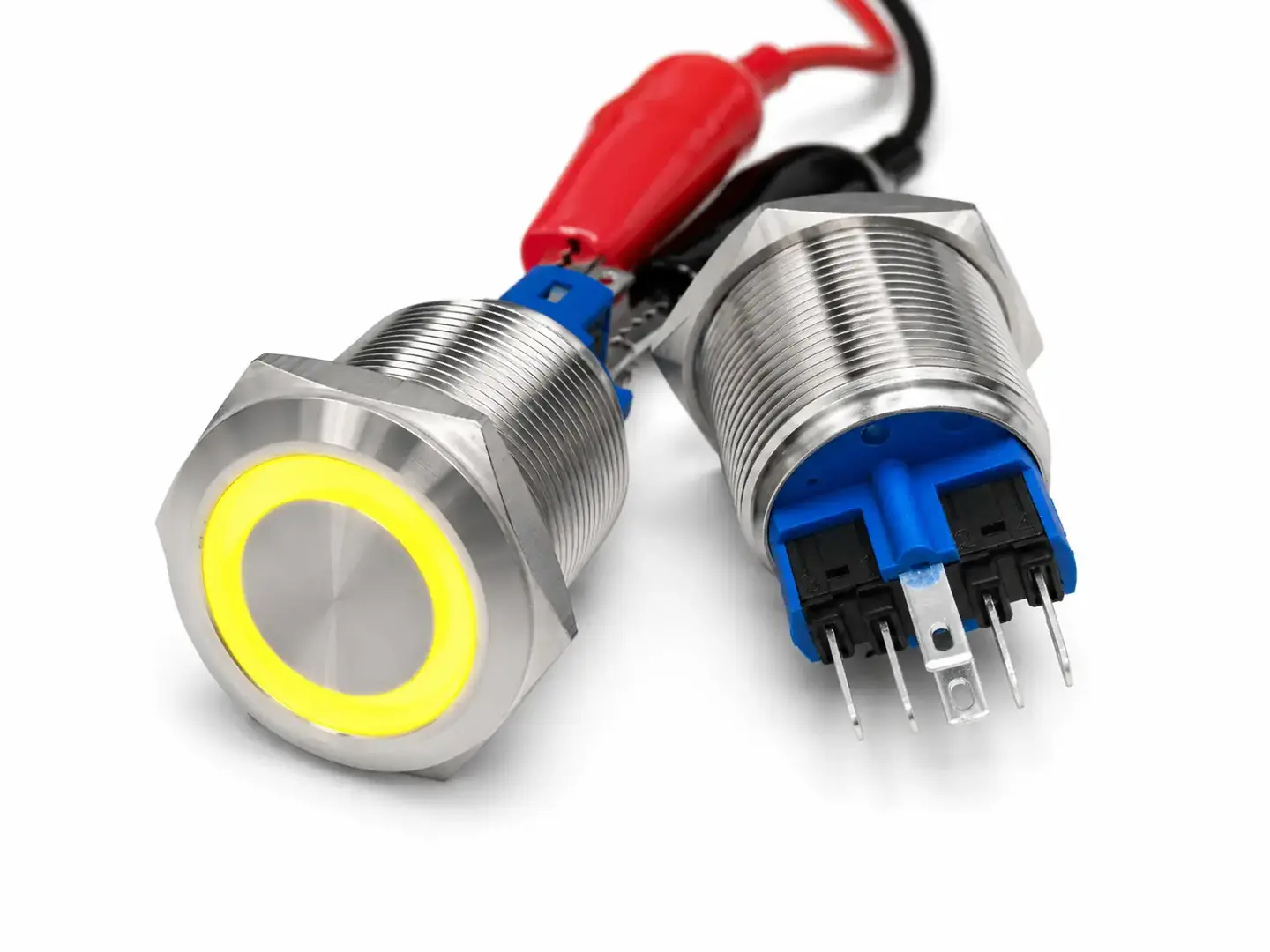 Pulsante monostabile da pannello Ø22 mm in acciaio inox con anello LED giallo, mostrato frontalmente e posteriormente con corpo filettato e terminali elettrici.